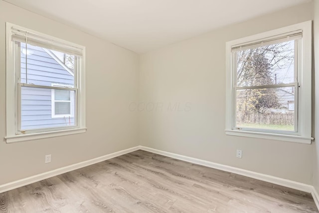 spare room with a wealth of natural light and light hardwood / wood-style flooring