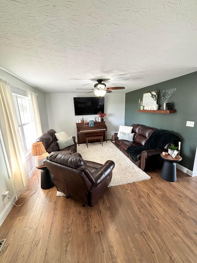 living room featuring hardwood / wood-style floors, ceiling fan, and a textured ceiling