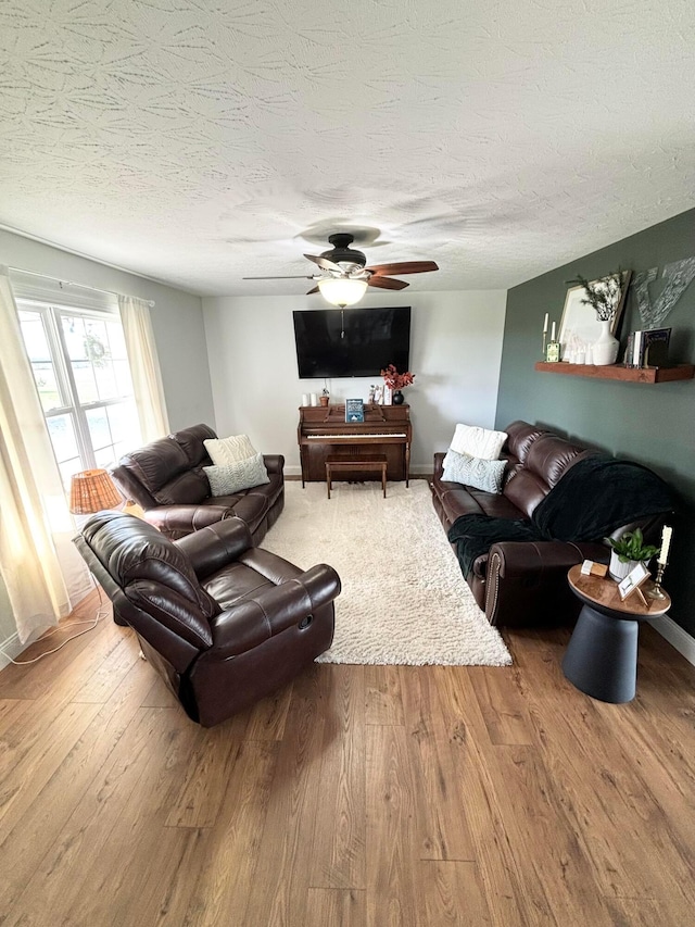 living room with hardwood / wood-style floors, ceiling fan, and a textured ceiling