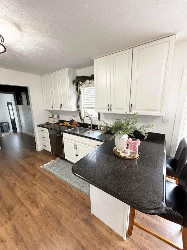 kitchen featuring dishwasher, sink, dark hardwood / wood-style floors, a textured ceiling, and white cabinetry