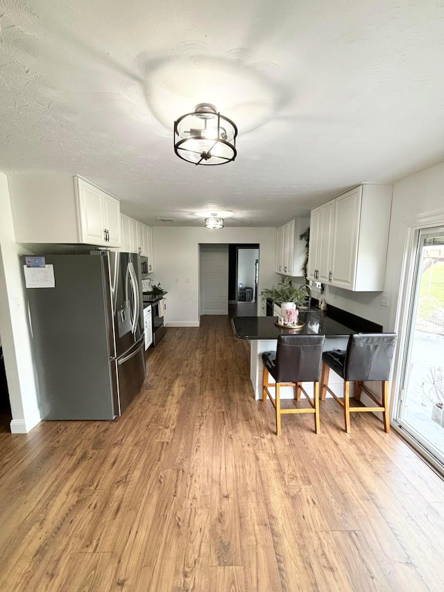 kitchen with white cabinets, light hardwood / wood-style floors, and stainless steel refrigerator with ice dispenser