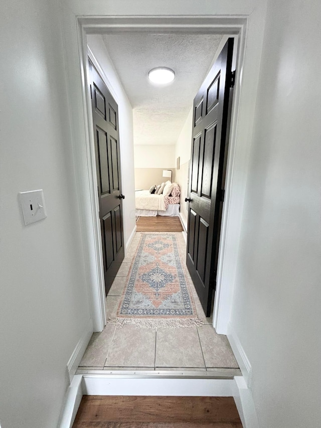 hallway featuring light tile patterned floors and a textured ceiling