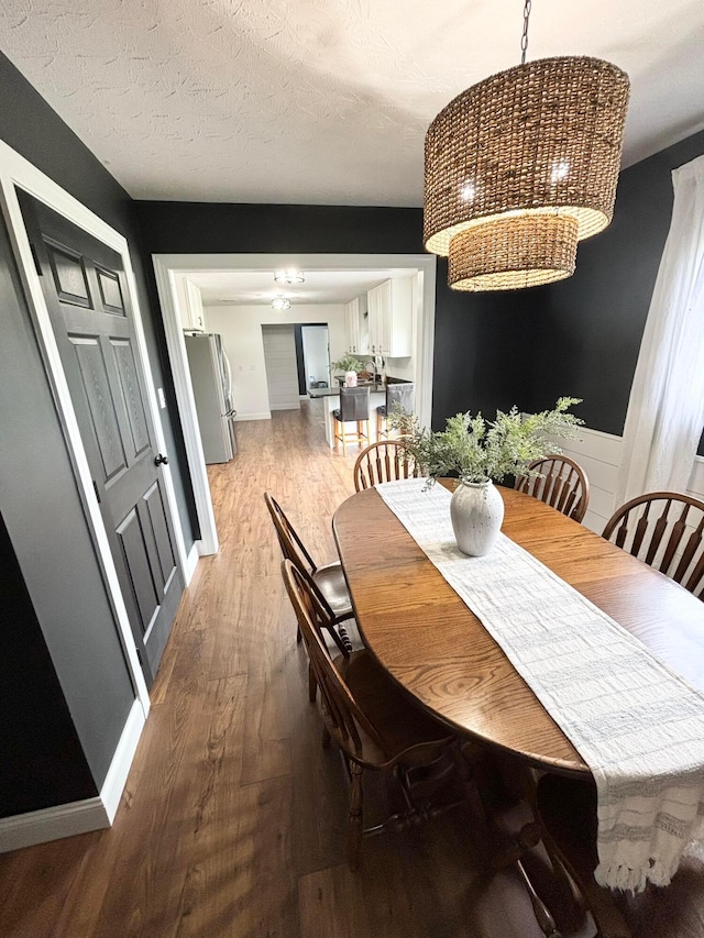 dining space with ceiling fan, wood-type flooring, and a textured ceiling