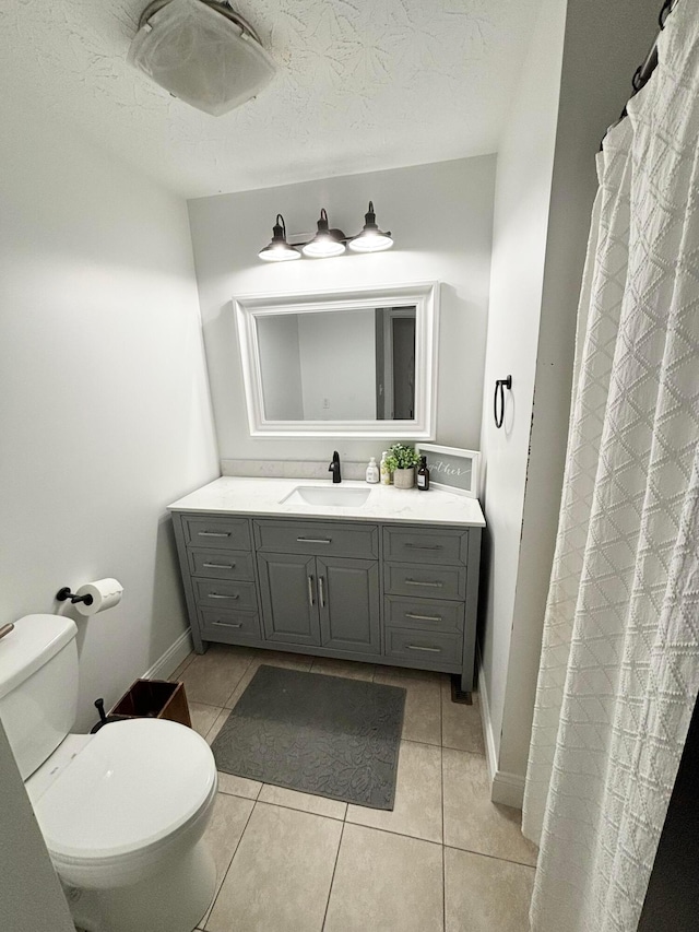 bathroom with tile patterned floors, vanity, a textured ceiling, and toilet