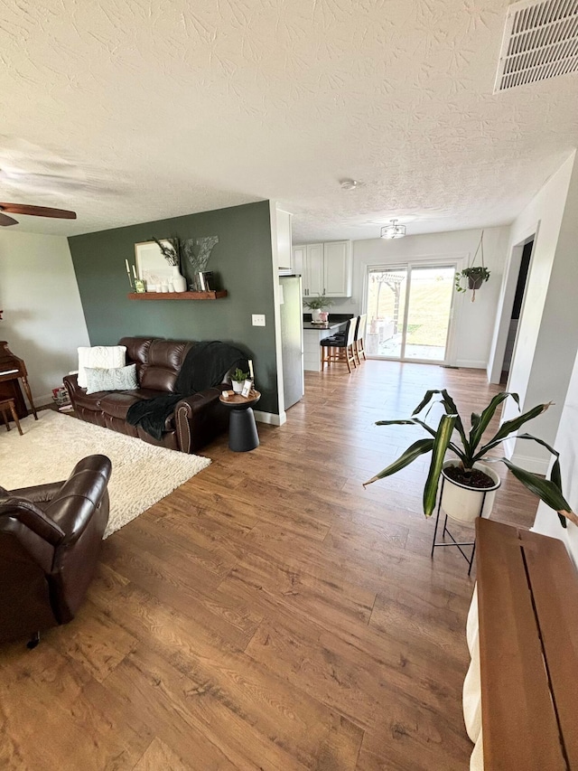 living room featuring hardwood / wood-style floors, a textured ceiling, and ceiling fan