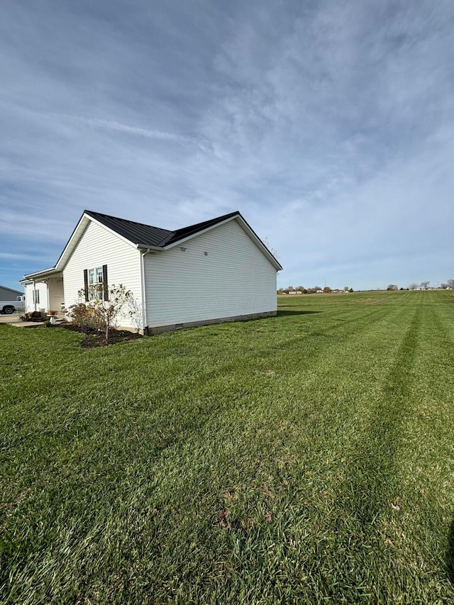 view of side of property featuring a lawn and a rural view