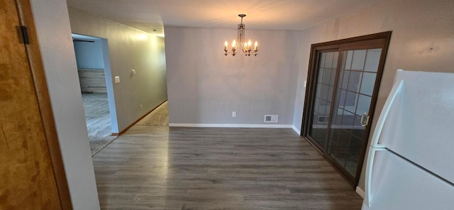 unfurnished dining area with a chandelier and dark wood-type flooring