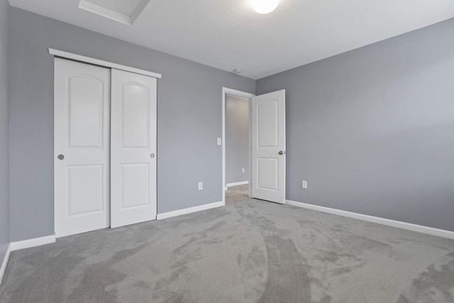 unfurnished bedroom featuring light carpet, a textured ceiling, and a closet