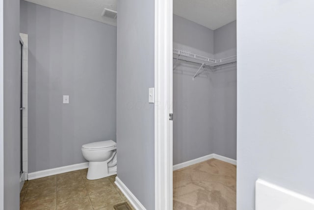 bathroom featuring tile patterned floors, toilet, and a textured ceiling