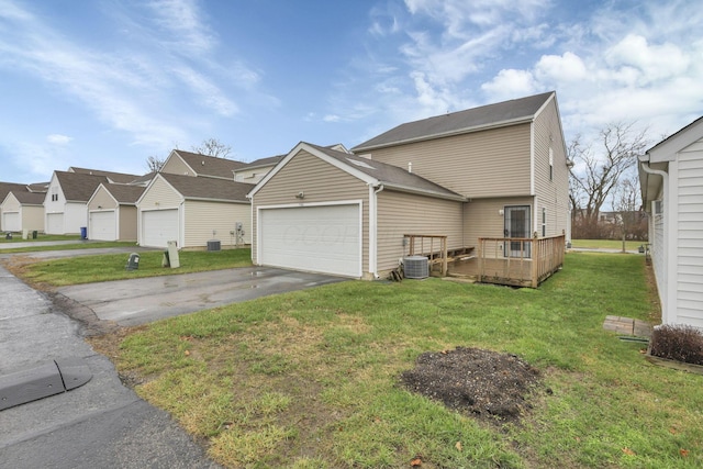 view of front of property featuring a garage, a wooden deck, a front yard, and central AC