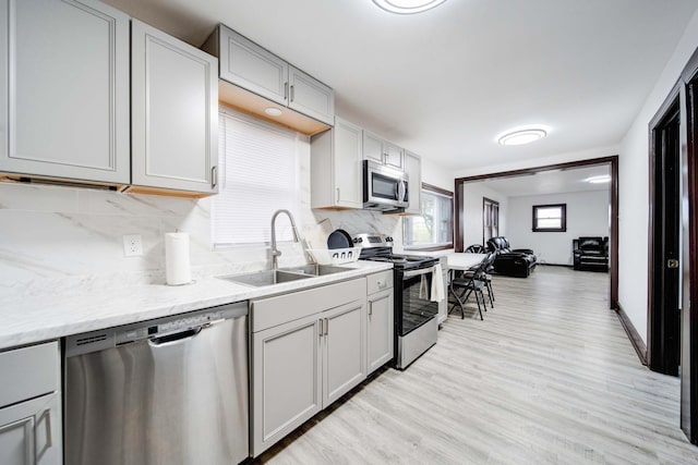 kitchen with decorative backsplash, stainless steel appliances, light hardwood / wood-style floors, and sink