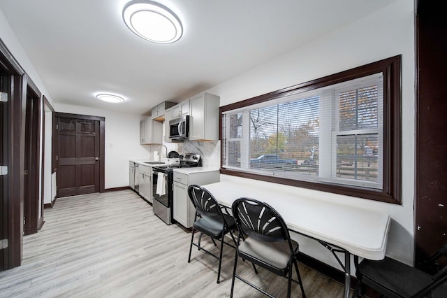 kitchen featuring backsplash, sink, light wood-type flooring, and appliances with stainless steel finishes