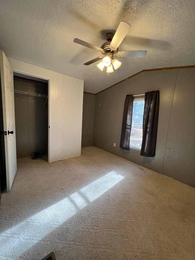 unfurnished bedroom with lofted ceiling, carpet flooring, ceiling fan, a textured ceiling, and a closet