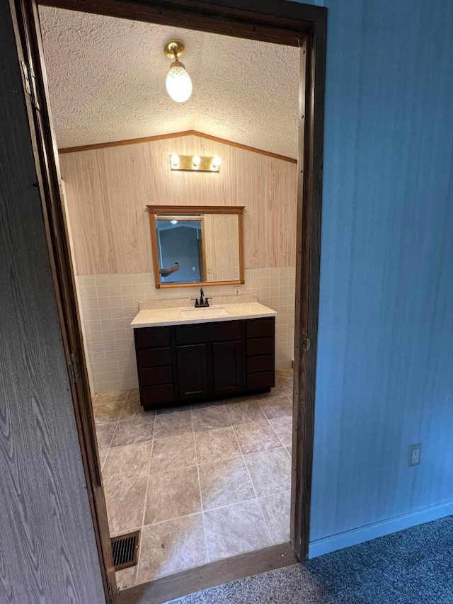 bathroom featuring vanity, a textured ceiling, and vaulted ceiling