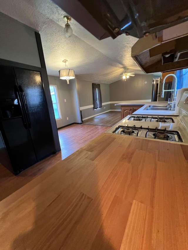 kitchen with ceiling fan, sink, white range oven, hardwood / wood-style floors, and a textured ceiling