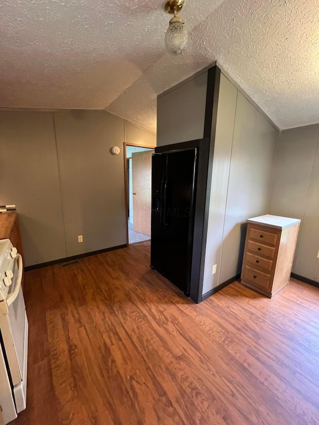 additional living space featuring hardwood / wood-style flooring, a textured ceiling, and vaulted ceiling