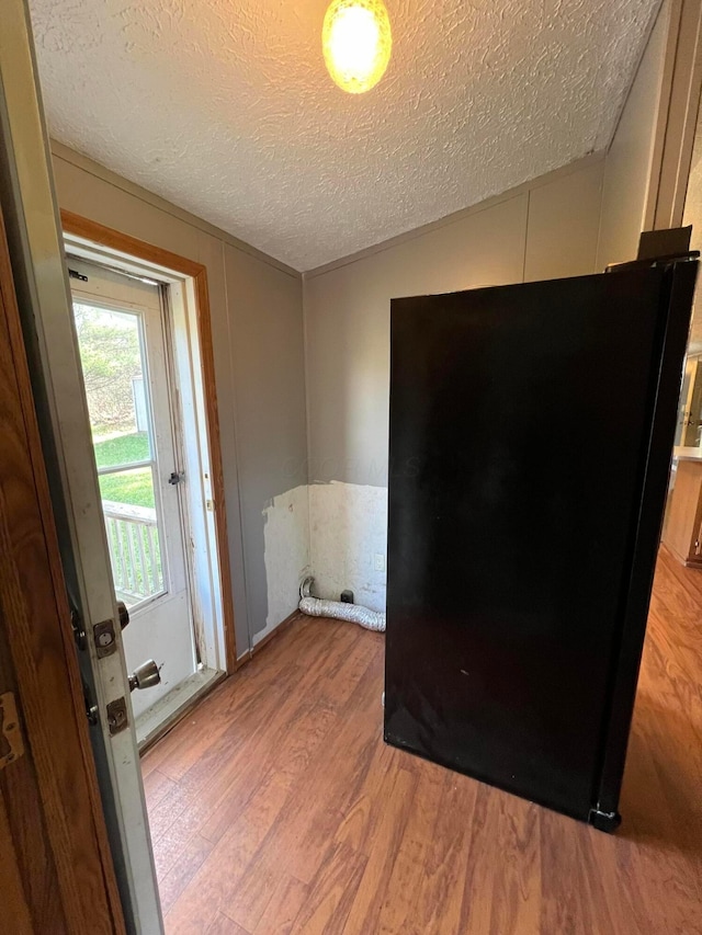 empty room with vaulted ceiling, hardwood / wood-style floors, and a textured ceiling