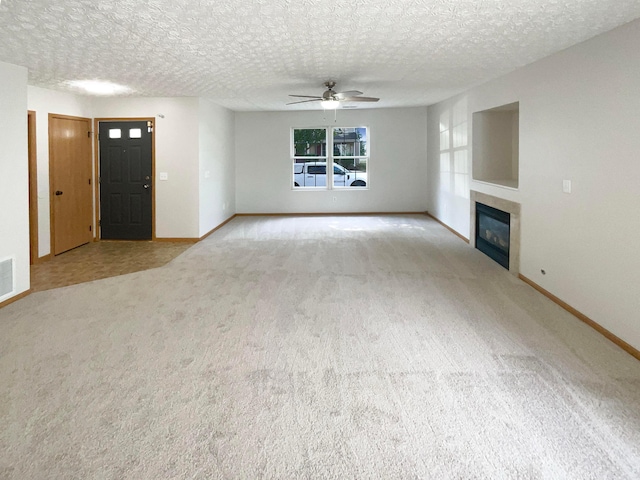 unfurnished living room featuring a textured ceiling, light colored carpet, and ceiling fan