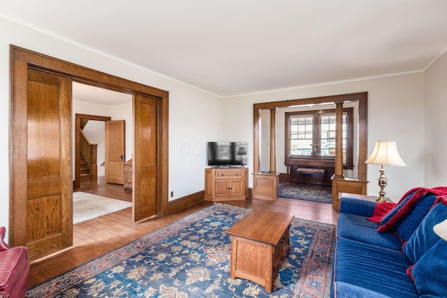 living area featuring stairs, baseboards, wood finished floors, and crown molding