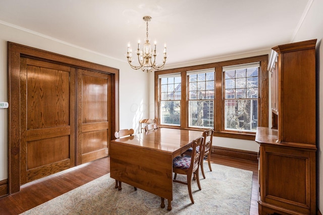 dining room featuring a chandelier, baseboards, and wood finished floors