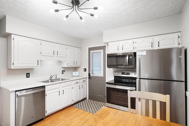 kitchen featuring white cabinetry, sink, light hardwood / wood-style flooring, a textured ceiling, and appliances with stainless steel finishes