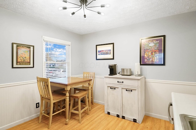 dining space featuring an inviting chandelier, a textured ceiling, and light hardwood / wood-style flooring