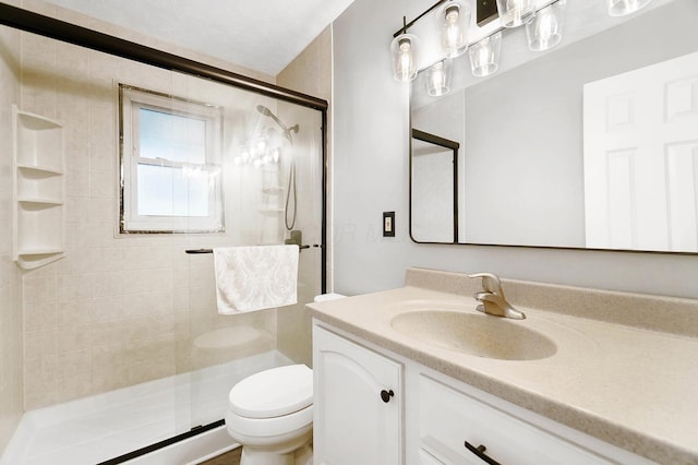 bathroom with a shower with door, vanity, and toilet