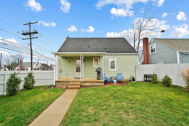 back of property with a lawn and a porch