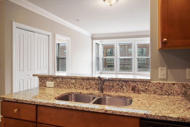 kitchen featuring dishwashing machine, crown molding, light stone countertops, and sink