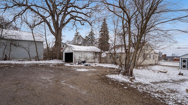 snowy yard with a garage and an outbuilding