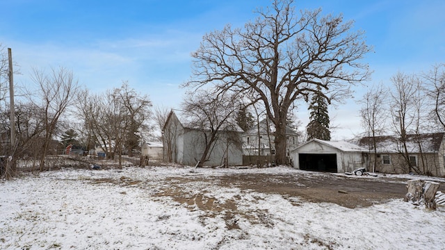 snowy yard featuring a detached garage and an outdoor structure