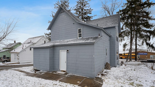 snow covered property featuring a shingled roof