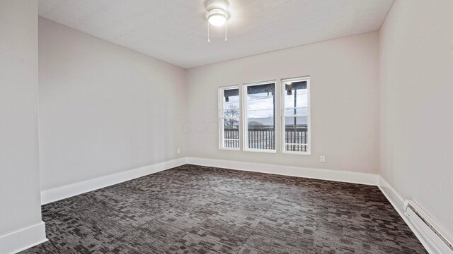 unfurnished room with baseboards, baseboard heating, and dark colored carpet