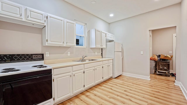 kitchen with a sink, electric stove, light countertops, light wood-type flooring, and freestanding refrigerator