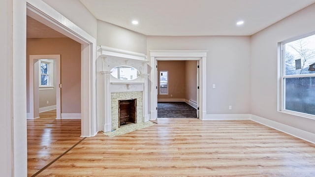 unfurnished living room featuring plenty of natural light, wood finished floors, and a fireplace with flush hearth