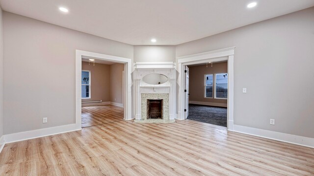 unfurnished living room with a fireplace with flush hearth, recessed lighting, baseboards, and wood finished floors