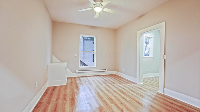 empty room featuring light wood-type flooring, a baseboard radiator, and baseboards