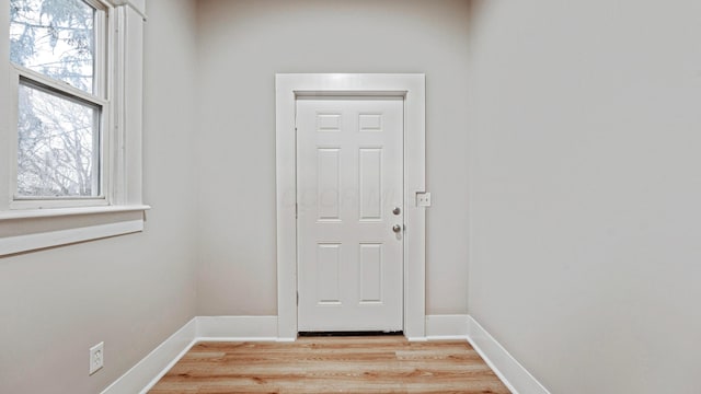 doorway to outside with a healthy amount of sunlight, light wood-style floors, and baseboards