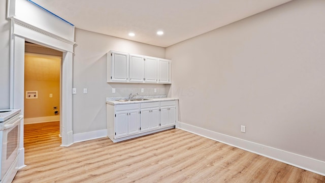 bar featuring light wood finished floors, white electric stove, baseboards, a sink, and recessed lighting