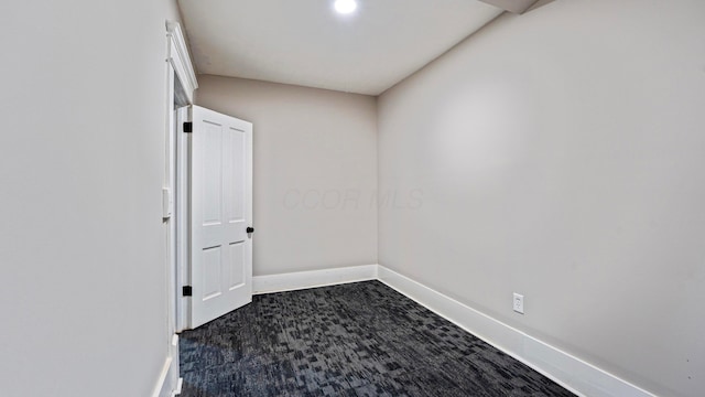 spare room with dark colored carpet and baseboards