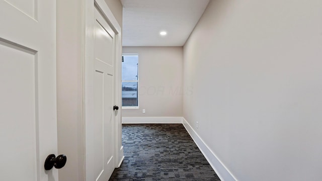 hallway with dark carpet and baseboards