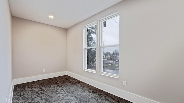 unfurnished room with dark colored carpet, recessed lighting, and baseboards