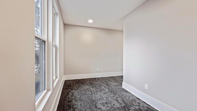 empty room featuring baseboards, dark colored carpet, and recessed lighting