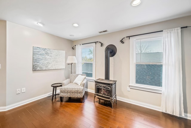 sitting room featuring a wood stove and dark wood-type flooring