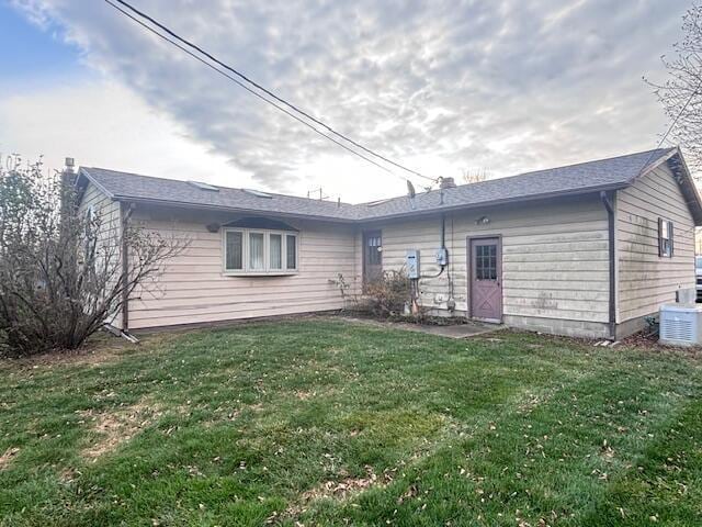 rear view of property with a lawn and central AC unit