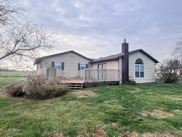 back of property with a yard and a wooden deck