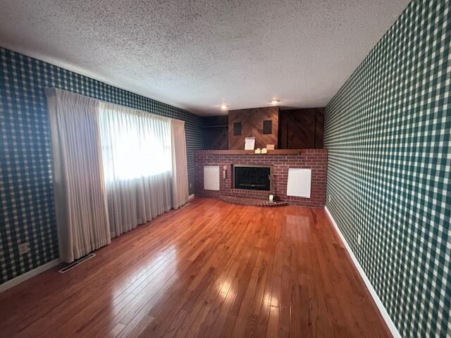 unfurnished living room featuring a fireplace, hardwood / wood-style floors, and a textured ceiling