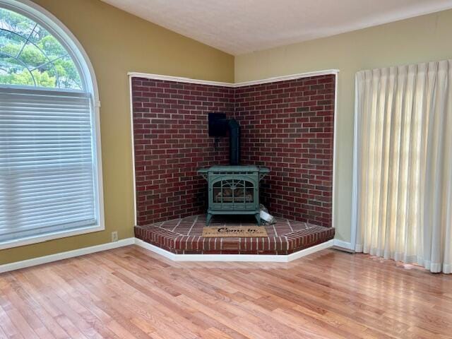 unfurnished living room with a wood stove, wood-type flooring, and vaulted ceiling