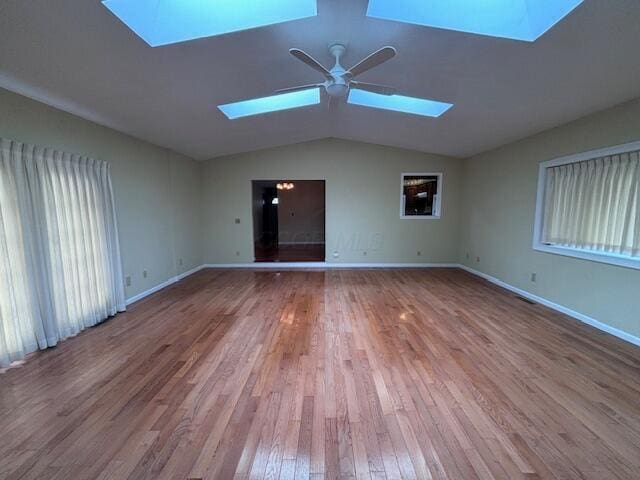 spare room featuring ceiling fan, lofted ceiling with skylight, and hardwood / wood-style flooring