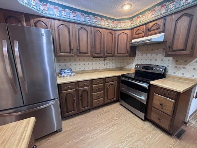 kitchen with appliances with stainless steel finishes, light wood-type flooring, a textured ceiling, and dark brown cabinetry